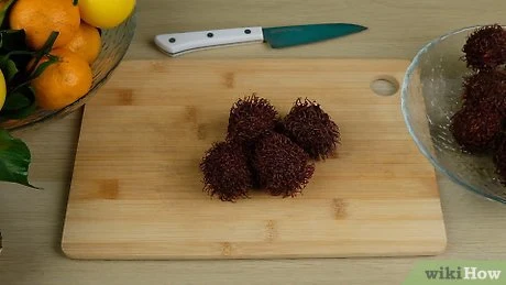 Rambutany na dřevěném prknu s citrusem v pozadí