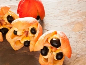 Otevřené ovoce ackee s oranžovou dužinou a černými semeny.