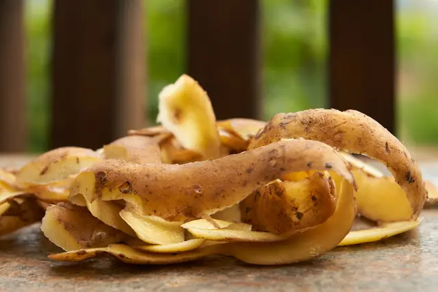 Svazek čerstvých bramborových slupek na kamenné ploše.