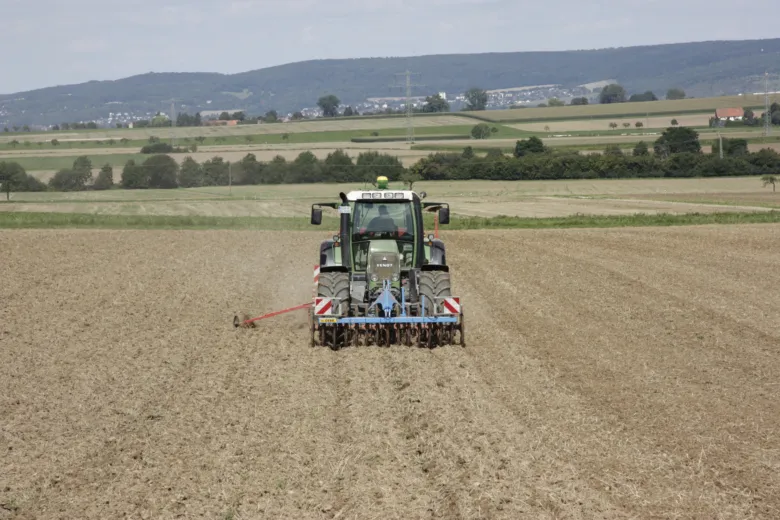 Traktor zasévá pole řepky na jaře.