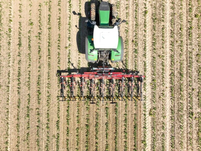Traktor s nářadím pro setí oves v řádku na poli.