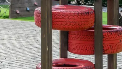 Červené pneumatiky na dřevěných sloupcích v zahradním hřišti.