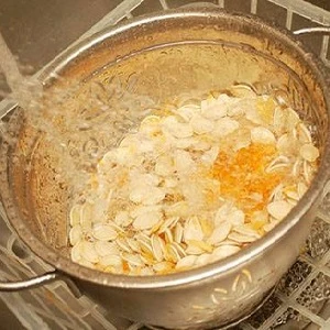 Mýdlování dýňových semínek v misce pod tekoucí vodou.