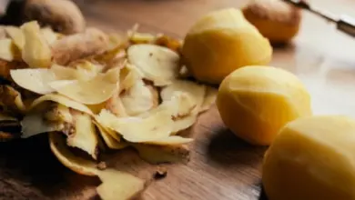 Odloupané žluté brambory s kůrkami na dřevěném povrchu.
