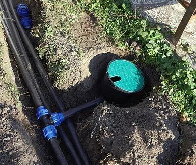 Instalace systému kapkového zavlažování s hadicemi a přírubami v zemi.