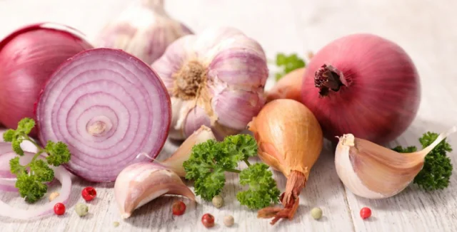 Červená cibule, česnek a petržel na dřevěném povrchu