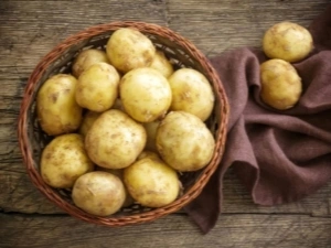Koš s čerstvými žlutými bramborami na dřevěném stole.