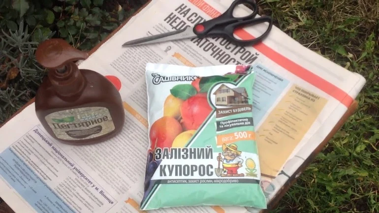 Balíček síranu železnatého s fľaškou na noviny v zahradě.