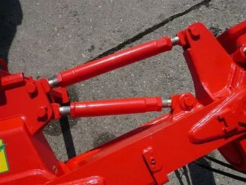 Červené hydraulické tyče na nářadí pro nastavení hloubky.