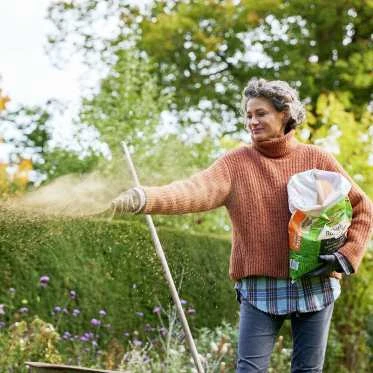 Woman spreading mulch in garden